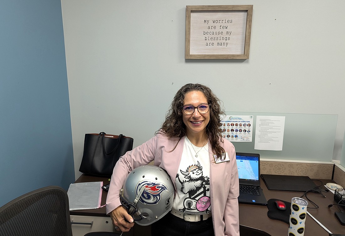 Monica Clean owner Monica Garcia with her old football helmet standing under one of her favorite slogans. Photo by Brent Woronoff